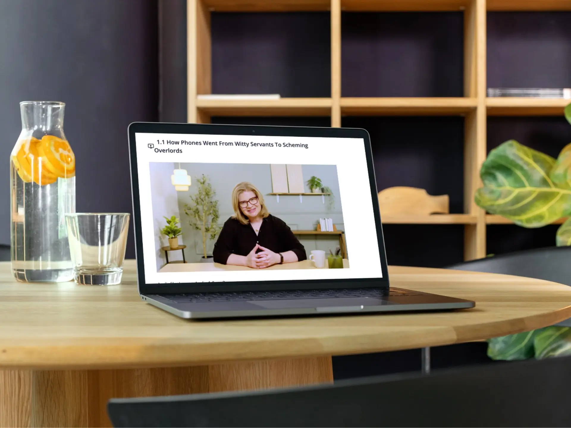 A laptop on a wooden table playing a lesson from the course, with Emmy on screen