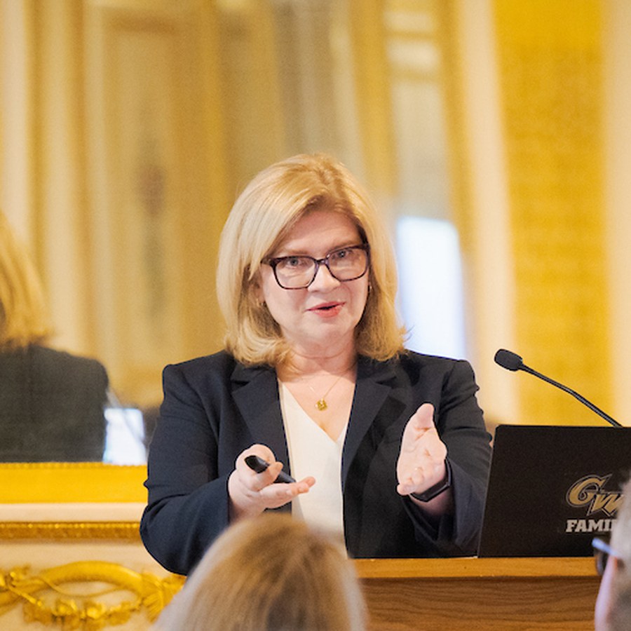 Emmy Laybourne mid-talk at the lectern, gesturing to the room