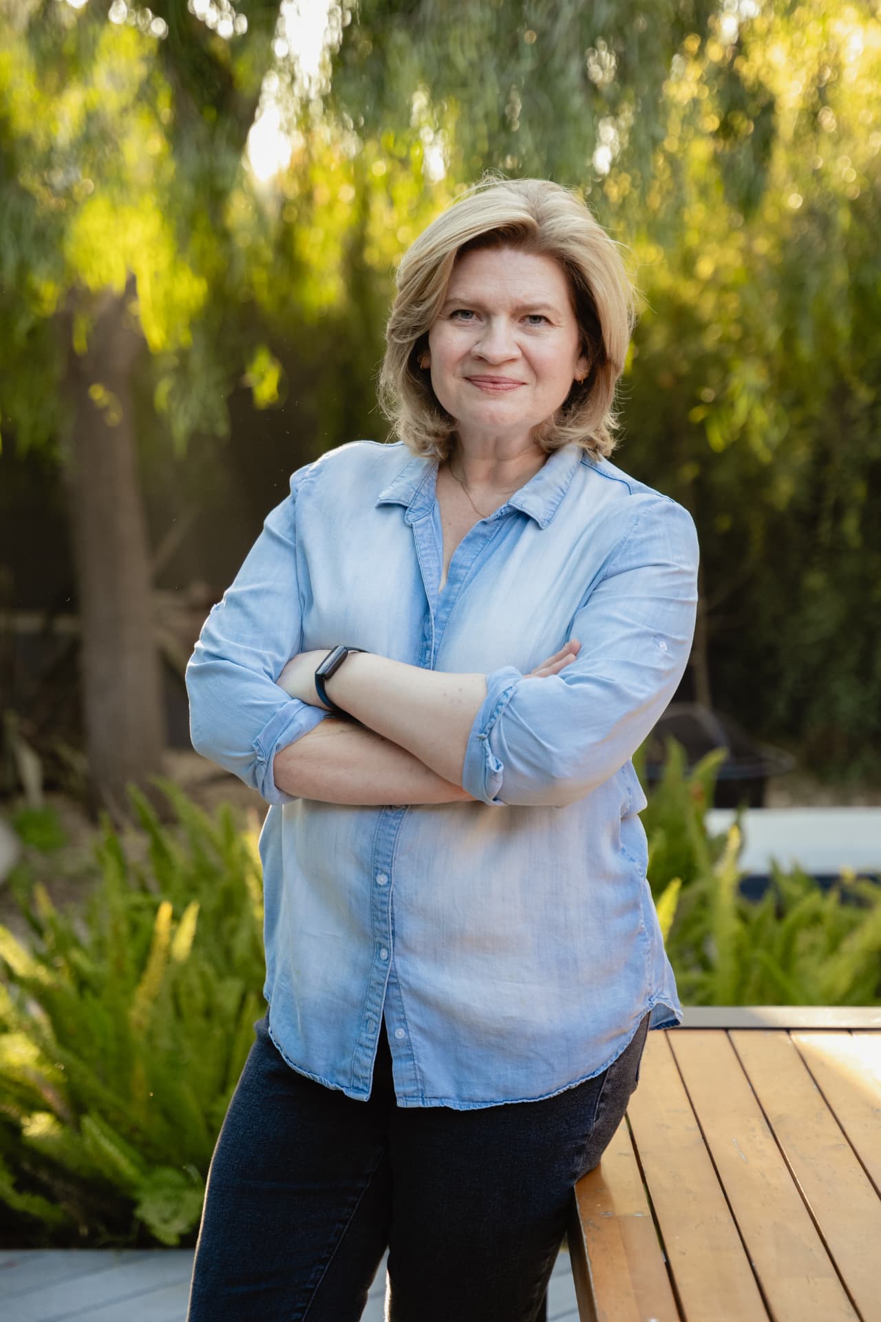 Emmy Laybourne smiling outdoors with her arms crossed